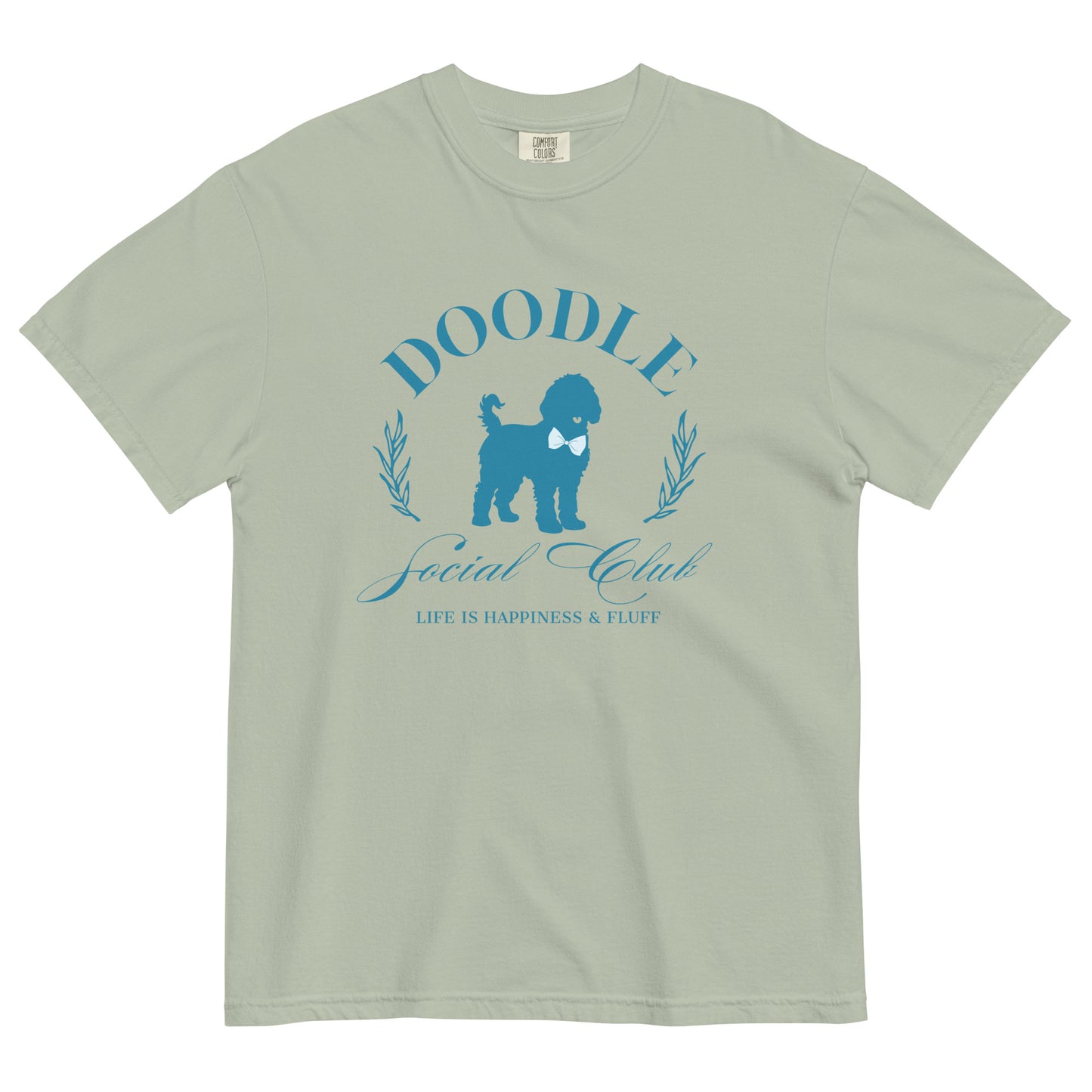 This Doodle Mom shirt displays the phrase, "Doodle Social Club" and the tag line "Live Like You're a Doodle Dog" below a graphic of a Doodle dog wearing a blue bow tie. The design is printed in blue on the front of a Comfort Colors short-sleeve T-shirt.