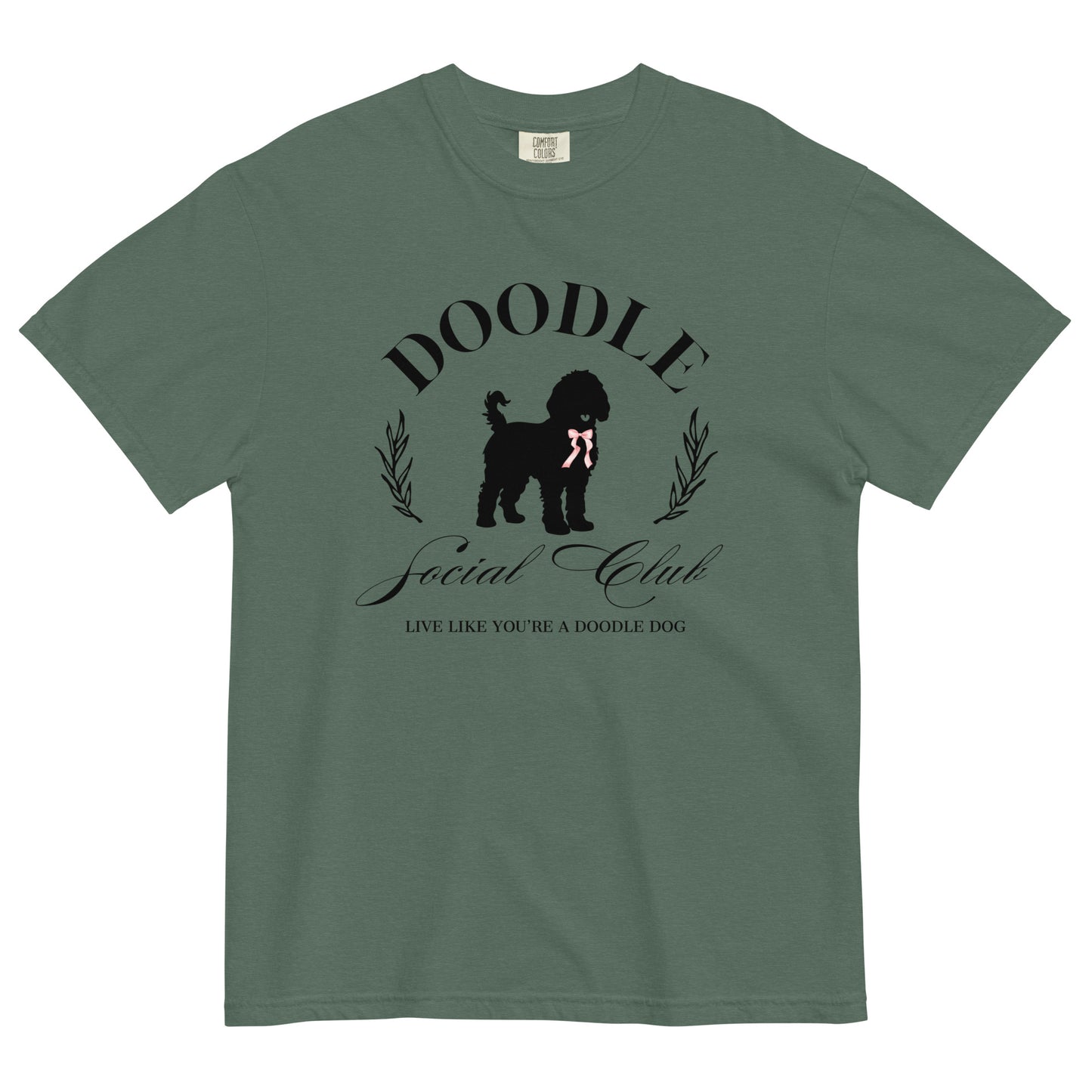 This Doodle Mom shirt displays the words, "Doodle Social Club" and the tag line "Live Like You're a Doodle Dog" below a graphic of a Goldendoodle dog wearing a pink ribbon. The design is printed on the front of a Comfort Colors T-shirt.