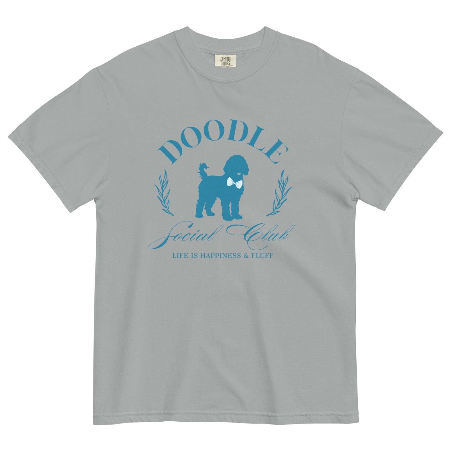 This Doodle Mom shirt displays the phrase, "Doodle Social Club" and the tag line "Live Like You're a Doodle Dog" below a graphic of a Doodle dog wearing a blue bow tie. The design is printed in light blue on the front of a Comfort Colors short-sleeve T-shirt.