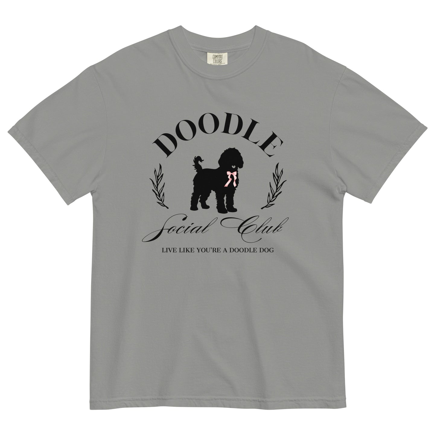 This Goldendoodle shirt features the words, "Doodle Social Club" and the tag line "Live Like You're a Doodle Dog" below a graphic of a Golden Doodle dog wearing a pink ribbon. The design is printed on the front of a Comfort Colors T-shirt in short sleeve.