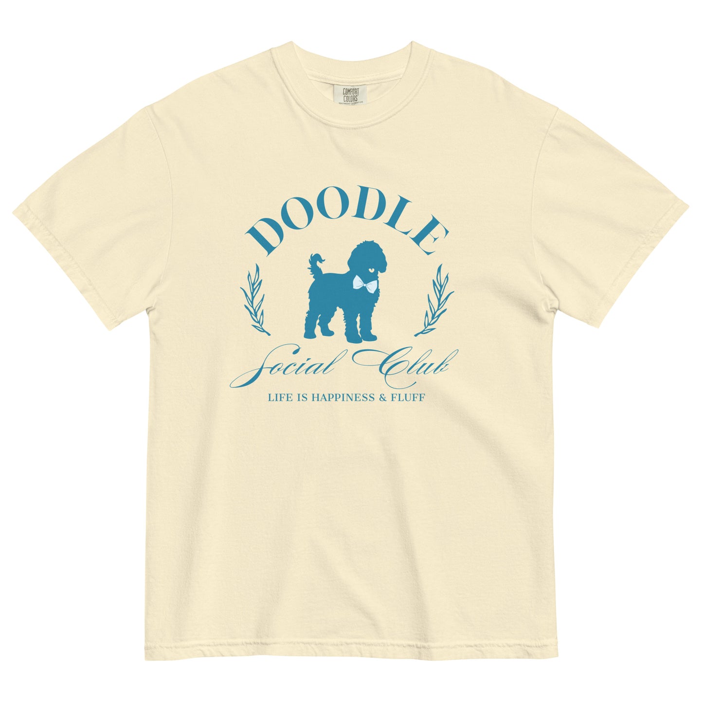 This Comfort Colors shirt displays the phrase, "Doodle Social Club" and the tag line "Live Like You're a Doodle Dog" below a graphic of a Doodle dog wearing a blue bow tie. The design is printed in blue on the front of the short-sleeve shirt