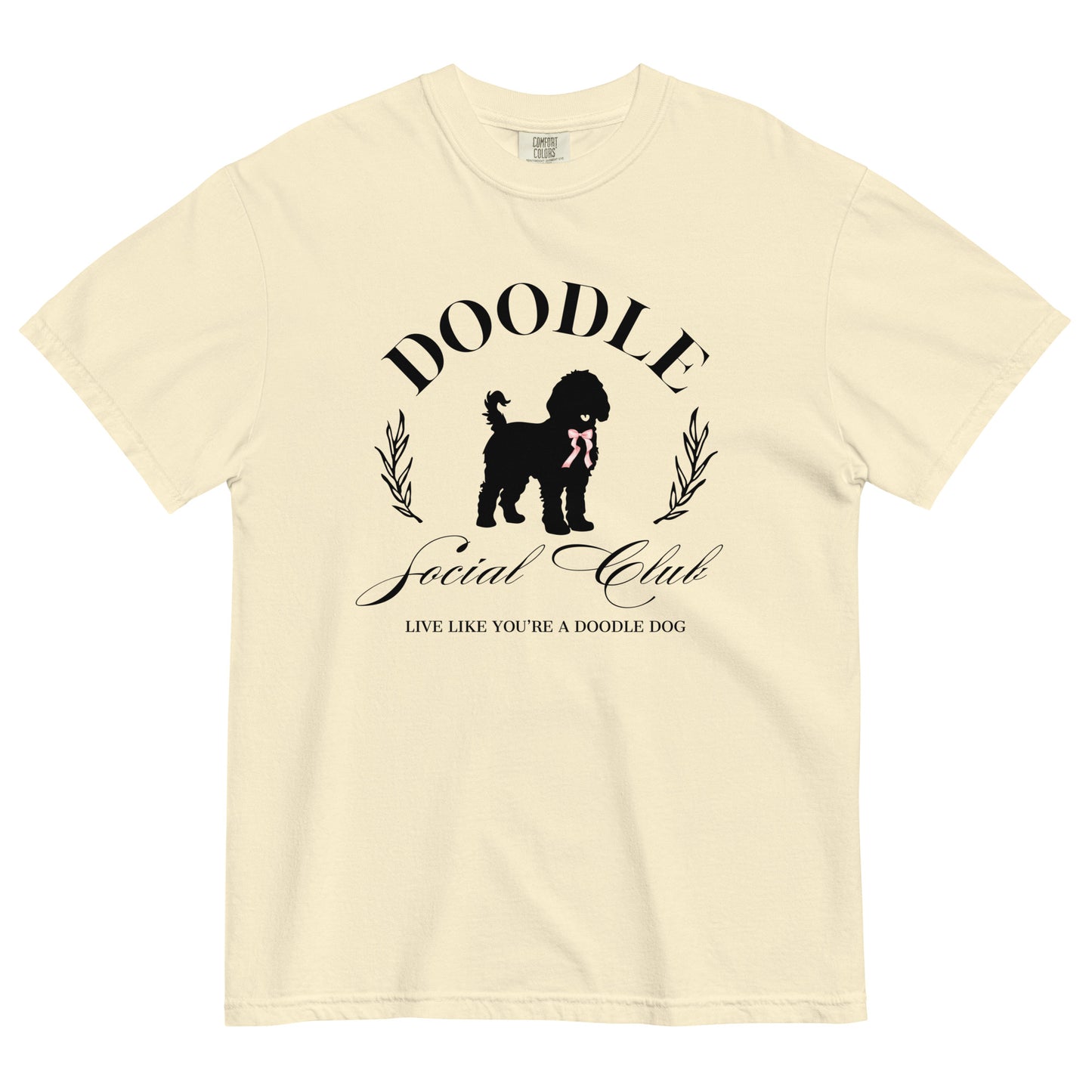 This Doodle Mom T-shirt features the message, "Doodle Social Club" and the tag line "Live Like You're a Doodle Dog" below a graphic of a Doodle dog wearing a pink ribbon. The design is printed on the front of a Comfort Colors T-shirt in ivory.