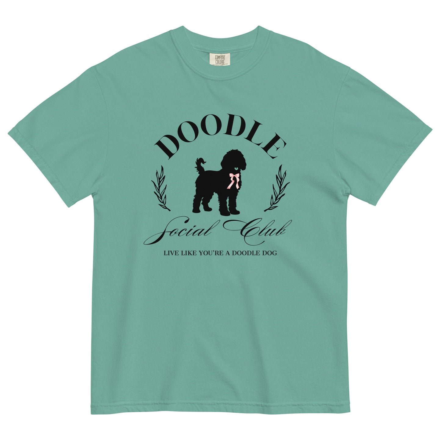 This Doodle Mom shirt features the words "Doodle Social Club" and the tag line "Live Like You're a Doodle Dog" below a graphic of a Doodle dog wearing a pink ribbon. The design is printed on the front of a Comfort Colors T-shirt in sea foam.