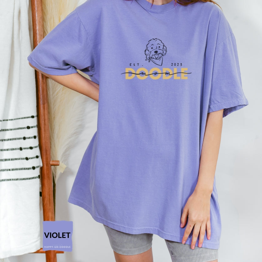 Goldendoodle Mom comfort colors t-shirt with Goldendoodle face and words "Doodle Mom Est 2023" in violet color