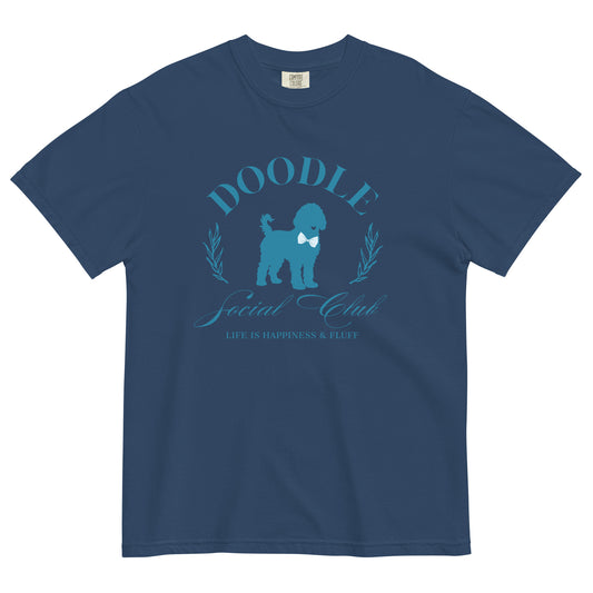 This Doodle Mom shirt displays the message, "Doodle Social Club" and the tag line "Live Like You're a Doodle Dog"  below a graphic of a  Doodle dog wearing a blue bow tie. The design is printed in light blue on the front of a navy Comfort Colors T-shirt.